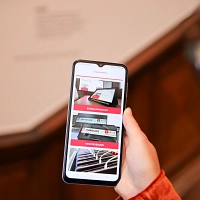 Eine Frau schaut auf ihr Smartphone auf dem die Seite des Medienzentrums Marburg geöffnet ist.