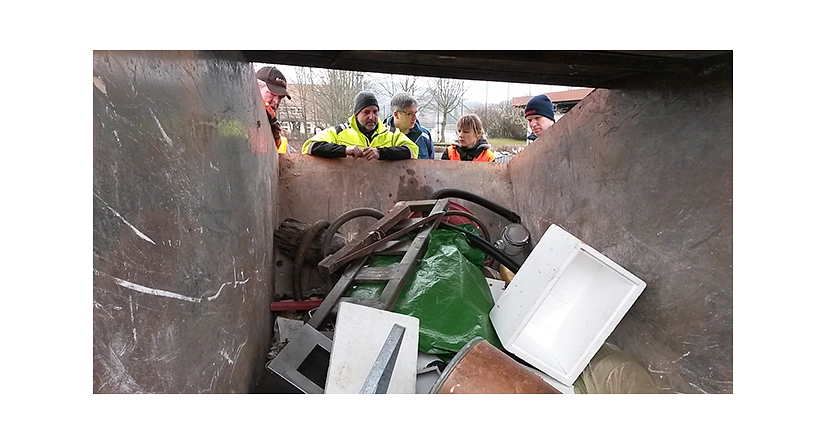 Das Foto zeigt Aktive des Sauberhaften Frühjahrsputz in Elnhausen wie sie in die gefüllte Abfallmulde schauen.&nbsp;&copy;&nbsp;DBM