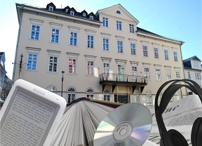 Außenansicht der Stadtbücherei als Collage mit Buch, E-Book-Reader, Kopfhörer, CD © Universitätsstadt Marburg